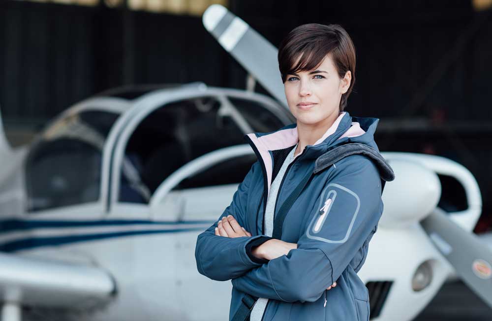 female pilot standing in front of single-engine airplane
