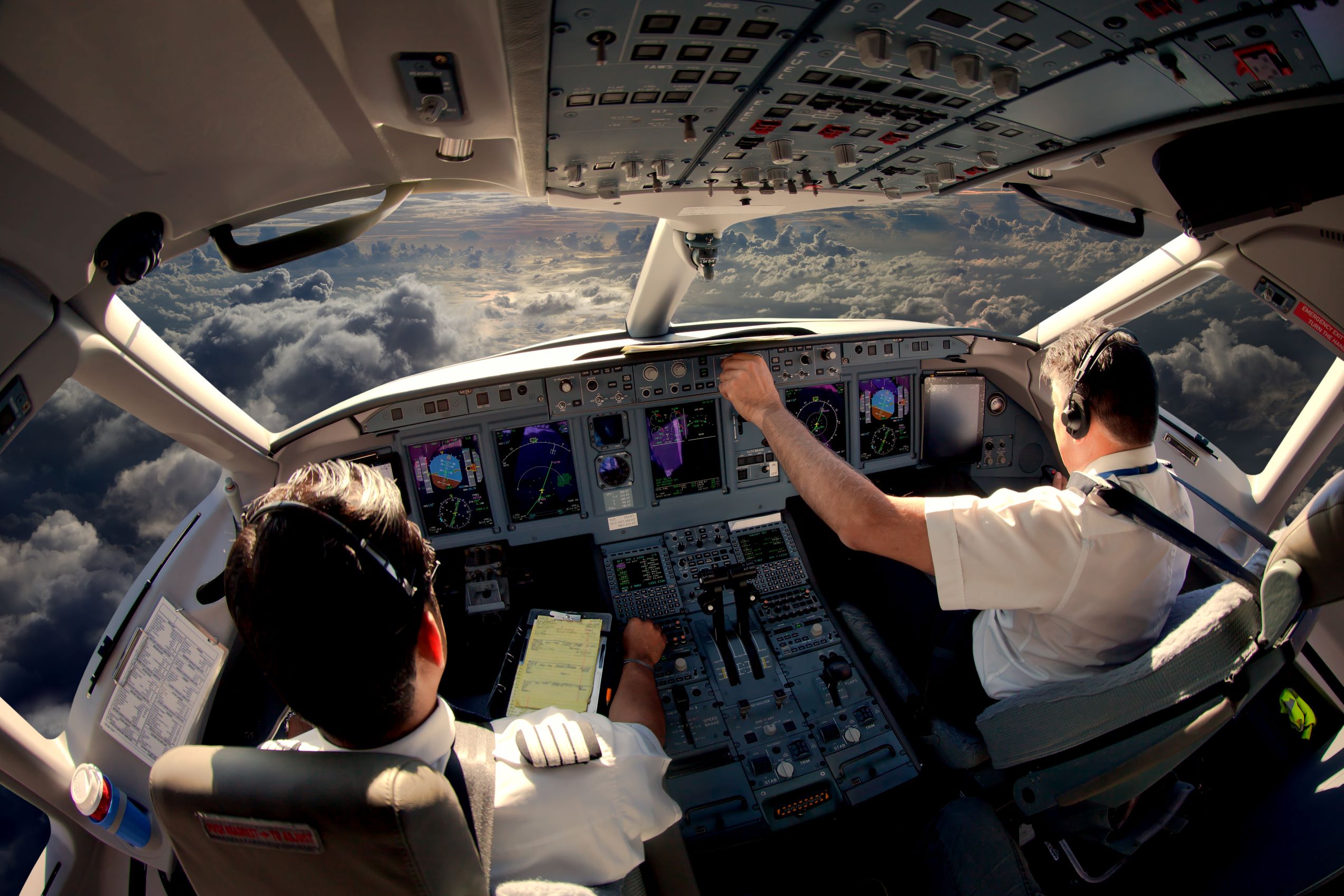 Two pilots working in the cockpit of a commercial plane.