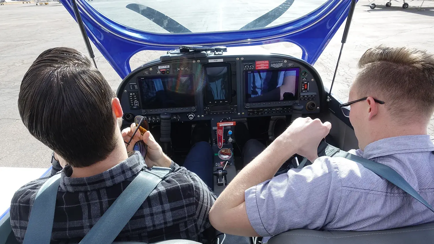 Two pilots in an open cockpit of a grounded plane.